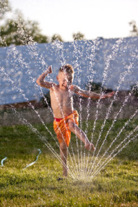 Boy running through sprinkler